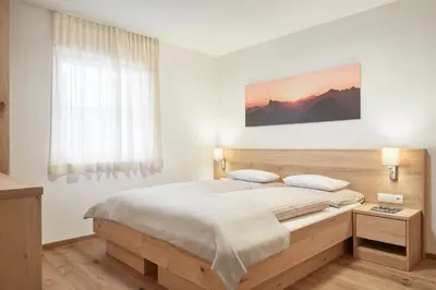 a bedroom with a large bed and a window at daHoam Appartamenti in Rasùn di Sotto