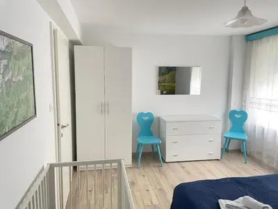a bedroom with a crib and a blue chair at SUITE DOLOMITI Appartamento in Falcade