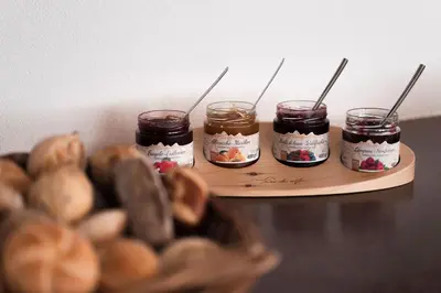 a wooden tray with four jars of jam and mushrooms at MyLiving - Hotel B&B by Majestic Resorts Dolomites in San Lorenzo di Sebato