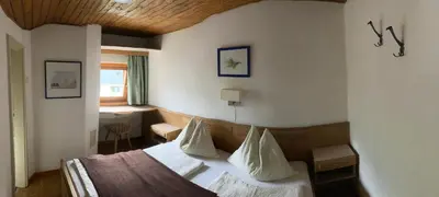 a hotel room with a bed with white sheets and pillows at Garni Guflhof in Caldaro
