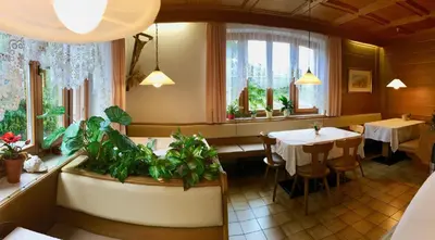 a restaurant with a table and chairs and windows at Garni Guflhof in Caldaro