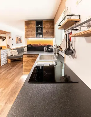 a kitchen with a sink and a living room at Sa Mont Home - Moderno appartamento con parcheggio, sauna e deposito sci in Bellamonte