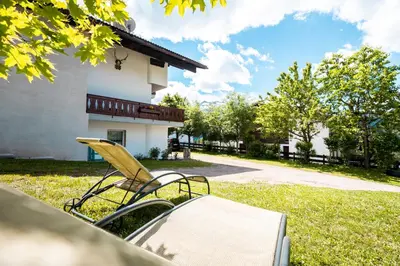 a couple of chairs and a table in front of a house at Sa Mont Home - Moderno appartamento con parcheggio, sauna e deposito sci in Bellamonte