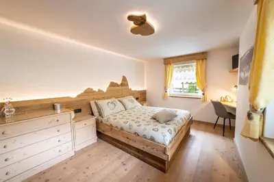 a bedroom with a bed and a desk and a window at Sa Mont Home - Moderno appartamento con parcheggio, sauna e deposito sci in Bellamonte
