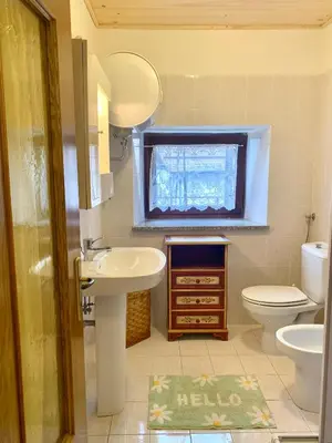 a bathroom with a sink and a toilet and a window at Casa Curti in Gosaldo