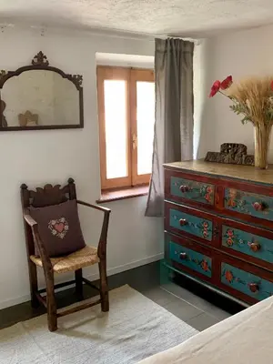 a bedroom with a dresser and a chair and a mirror at Casa Curti in Gosaldo