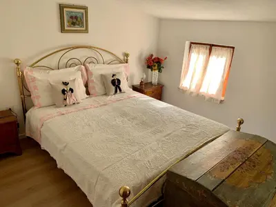 a bedroom with a large bed with two dolls on it at Casa Curti in Gosaldo