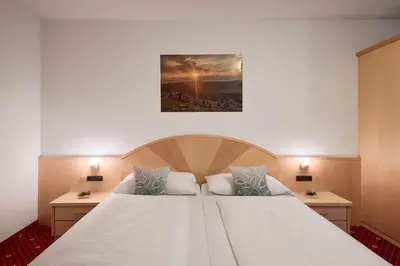 a bedroom with a large white bed with two tables at Zimmervermietung Zum Weissen Rössl in Sarntal