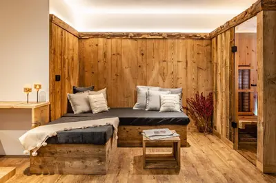 a bedroom with a wooden wall with a bed and a table at Bellevue Bruneck - Suites & Lofts in Brunico