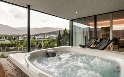 a bathroom with a tub and chairs on a balcony at Bellevue Bruneck - Suites & Lofts in Brunico