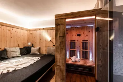 a bedroom with a bed and a balcony with mountains at Bellevue Bruneck - Suites & Lofts in Brunico