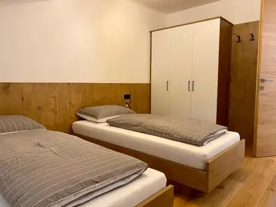 two twin beds in a room with a cabinet at Der Söllhof in Bressanone