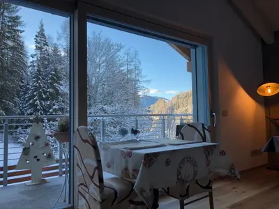 a dining room with a table and a large window at B&B Le Stagioni di Stava in Tesero