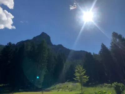 a sun is shining in the sky over a field at B&B Le Stagioni di Stava in Tesero