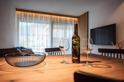 a bottle of wine sitting on a wooden table with two wine glasses at Deluxe Appartement Arve in Valdaora