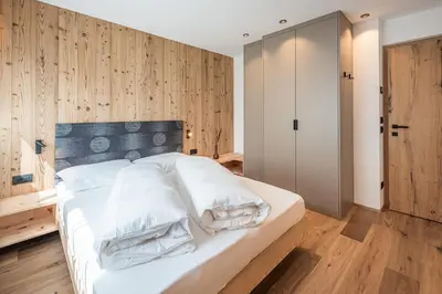 a bedroom with a white bed with wooden walls at Deluxe Appartement Arve in Valdaora