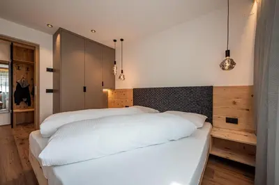 two beds in a bedroom with white sheets at Deluxe Appartement Arve in Valdaora