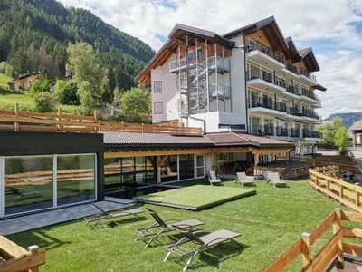 a building with a lawn and chairs in front of it at Active Alm Hotel in Moena