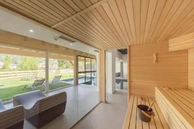 a living room with wood paneling and a large window at Active Alm Hotel in Moena