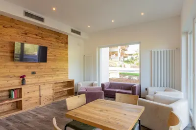 a living room with a table and a tv at Active Alm Hotel in Moena
