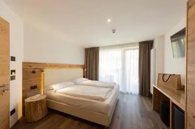 a bedroom with a bed and a table and a television at Active Alm Hotel in Moena