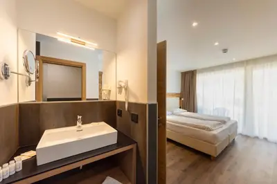 a bathroom with a sink and a bed at Active Alm Hotel in Moena