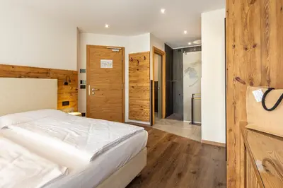 a bedroom with a white bed and wooden walls at Active Alm Hotel in Moena