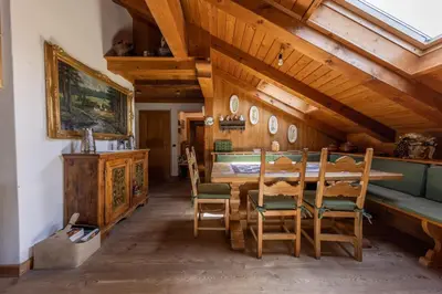 a dining room with a wooden table and chairs at Mansarda Belvedere - panoramica e wellness in San Vito di Cadore