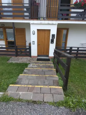 a house with a wooden door and a stone walkway at La casa di Grace nella valle incantantata in Carano