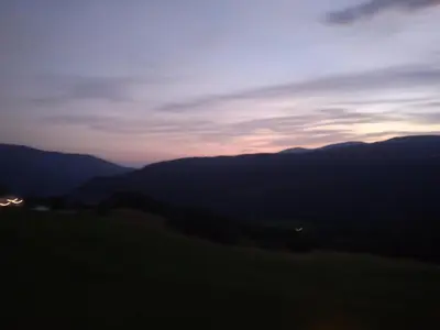 a view of a sunset from a field with mountains at La casa di Grace nella valle incantantata in Carano