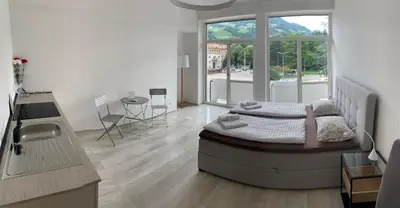 a bedroom with a bed and a large window at Alps Apartments Viktory in Bolzano