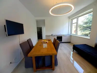 a living room with a table and chairs and a television at Alps Apartments Viktory in Bolzano
