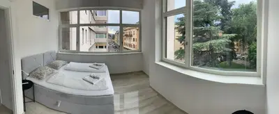 a bedroom with a bed and two large windows at Alps Apartments Viktory in Bolzano