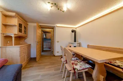 a kitchen and dining room with a wooden table and chairs at Ospitalità Diffusa Laste Dolomites Cèsa del Bèrba Jaco in Rocca Pietore