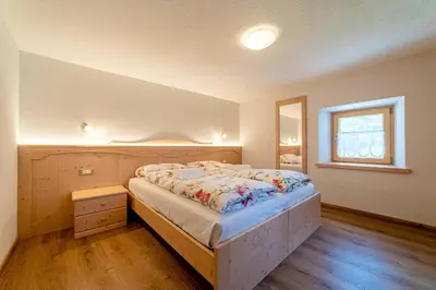 a bedroom with a bed and a window in it at Ospitalità Diffusa Laste Dolomites Cèsa del Bèrba Jaco in Rocca Pietore