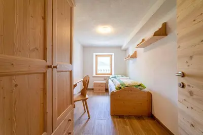 a small bedroom with a bed and a window at Ospitalità Diffusa Laste Dolomites Cèsa del Bèrba Jaco in Rocca Pietore