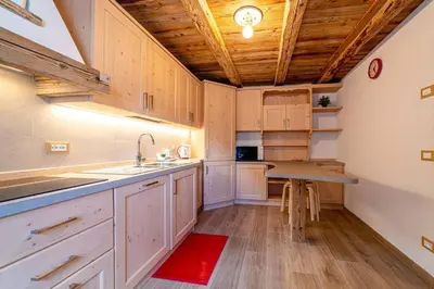 a kitchen with white cabinets and a wooden ceiling at Ospitalità Diffusa Laste Dolomites Cèsa del Bèrba Jaco in Rocca Pietore