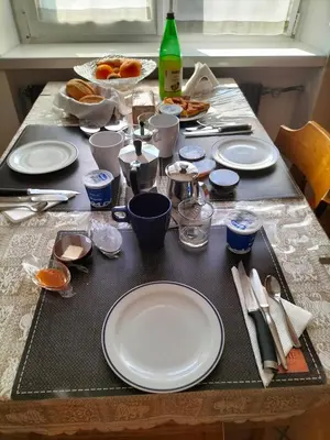 a table with white plates and utensils on it at le stanze di Saraswati in Salorno sulla Strada del Vino