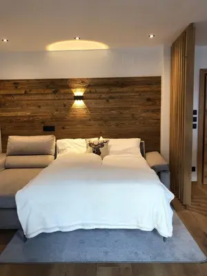 a bedroom with a large white bed with a wooden wall at Apartments Rainer - Val Gardena in Ortisei