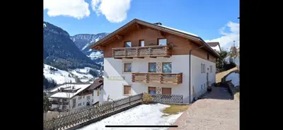 a house in the mountains with snow on the ground at Apartments Rainer - Val Gardena in Ortisei