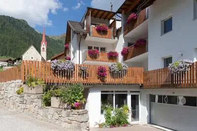 a building with flowerpots on the balconies and a church at Appartement Sonneck in Lappago