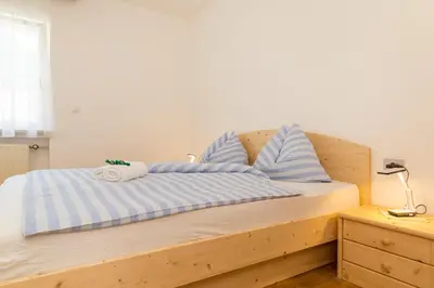 a bed with blue and white striped sheets and pillows at Appartement Sonneck in Lappago