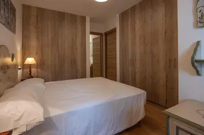 a bedroom with a white bed and wooden walls at Casa Maia in Cortina dʼAmpezzo