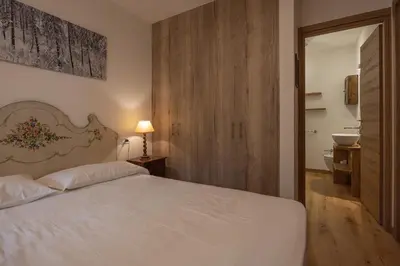 a bedroom with a white bed and a sink at Casa Maia in Cortina dʼAmpezzo