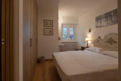 a bedroom with a white bed and a window at Casa Maia in Cortina dʼAmpezzo