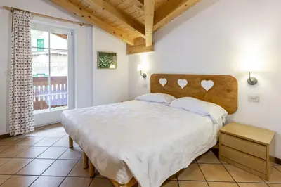 a bedroom with a large bed and a window at Casa Riz in Campitello di Fassa