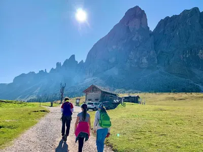 three people walking down a dirt road in front of a mountain at App. Franziska Villa Fabbrani in Bressanone