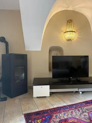 a living room with a flat screen tv and a table at Appartamento incantevole Fondo Val di Non in Fondo