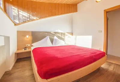 a bedroom with a bed with a red blanket at Zagler Appartments in Tirolo