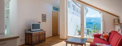 a living room with a red couch and a large window at Haus Pobitzer in Caldaro